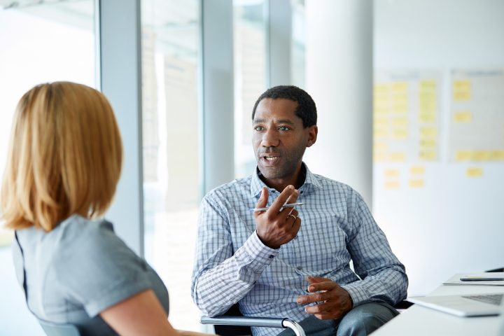 Shot of two colleagues talking together in a modern office